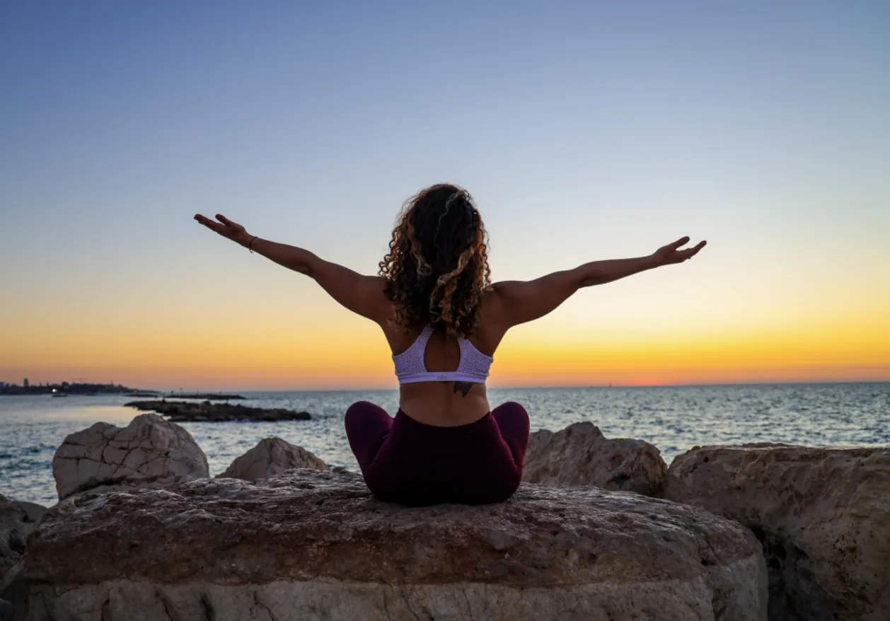 functional wellness happy woman post meditation sitting on rocks